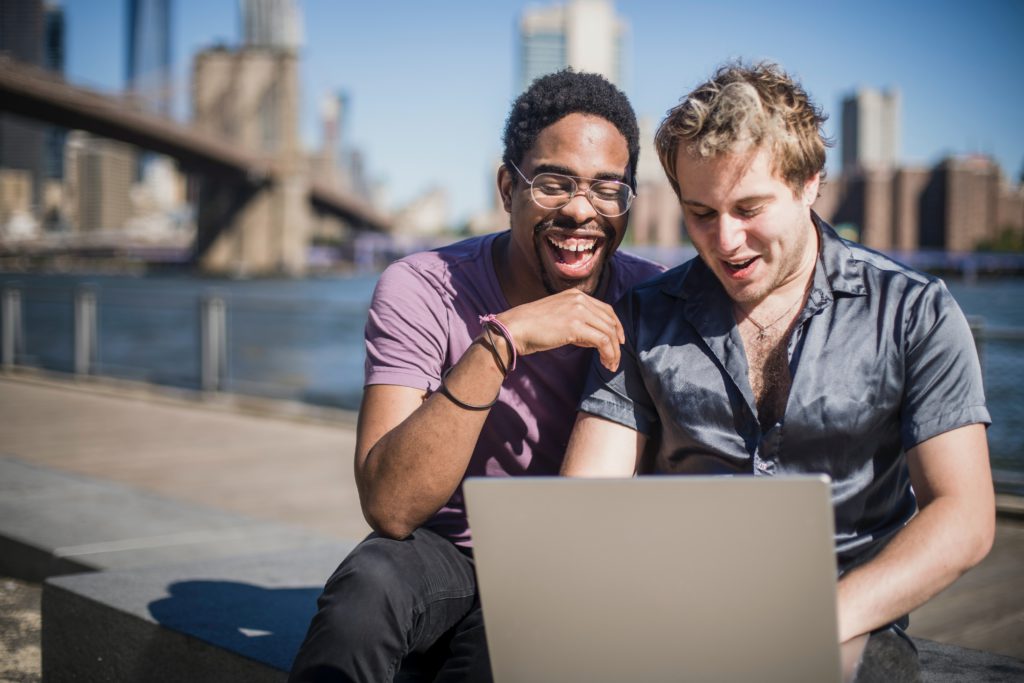Two people looking at a laptop with a city skyline behind them smiling