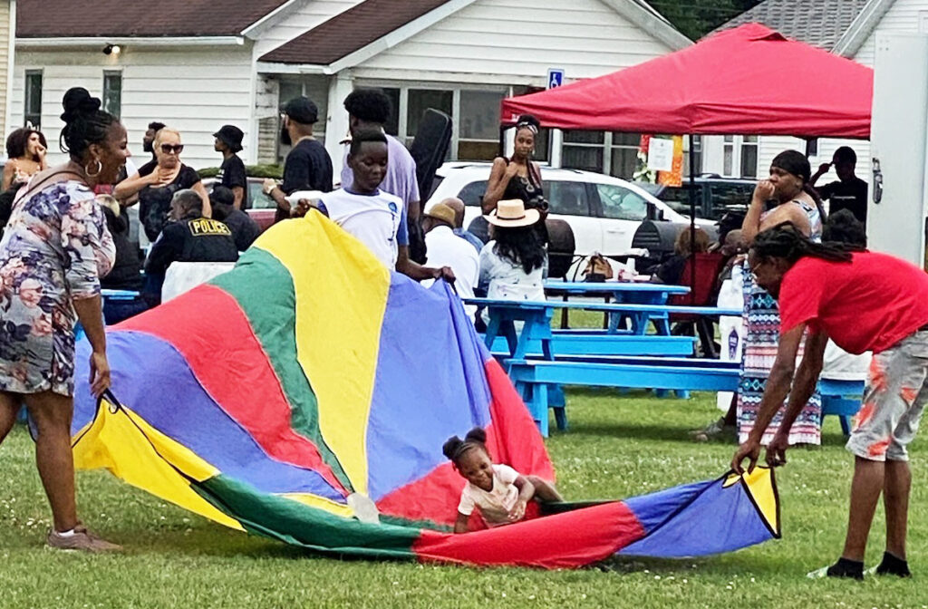 a child plays on a parachute at the Linden Avenue Farmer's Market