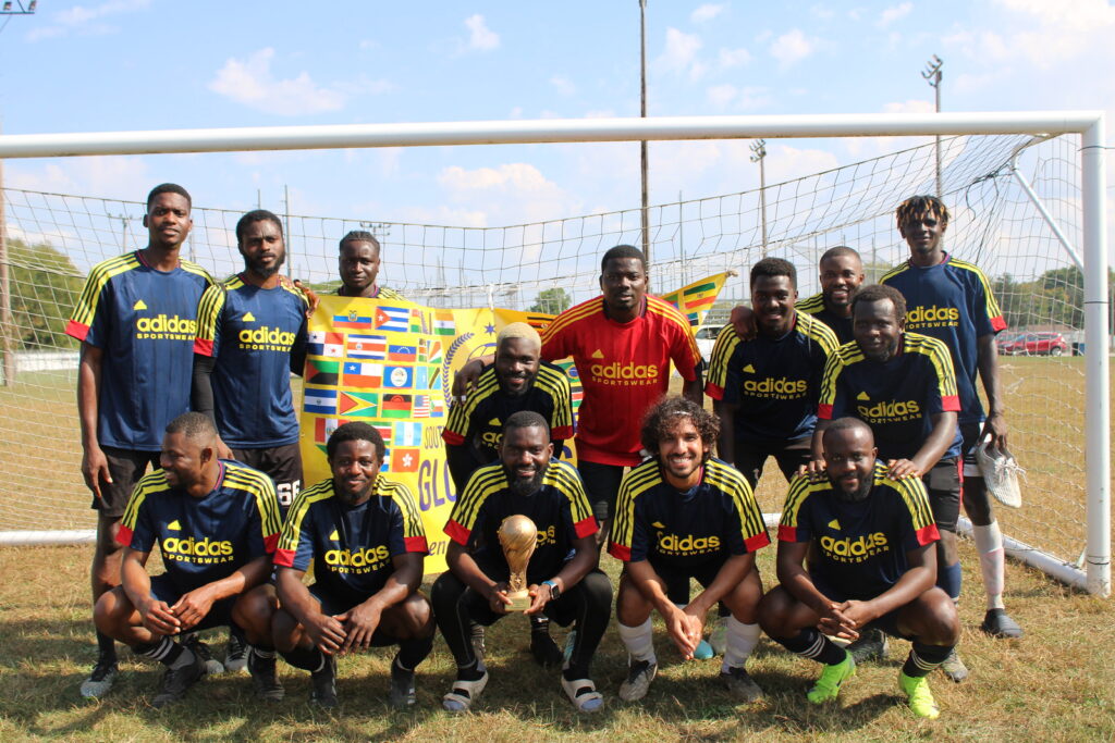 Team Ghageria poses in front of a soccer net with the trophy.